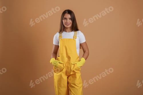 Preview: Hands in pockets, gardener is standing. Young pretty woman is against background in the studio