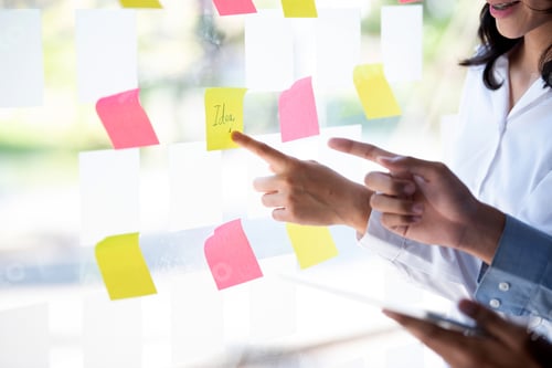 Preview: Group of business people putting sticky notes on glass wall at office.