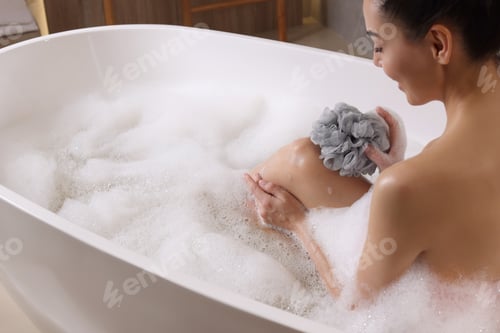 Preview: Woman taking bath with mesh pouf in tub, closeup