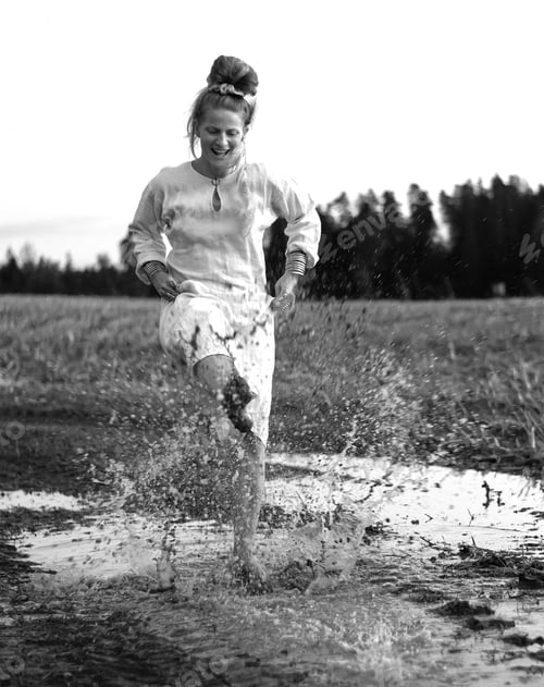 Preview: Crazy woman dancing barefoot and splashing in a puddle of mud in a field, freedom concept