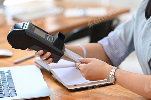 Preview: Young female customer swiping a debit card through payment terminal.