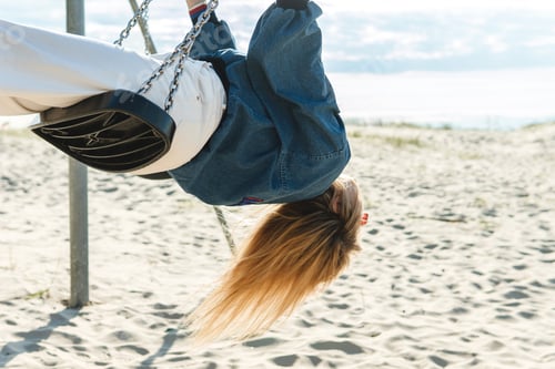 Preview: Young woman swinging on the swing at the sandy beach.