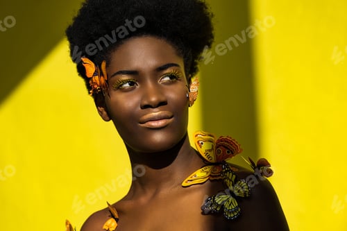 Preview: Smiling pretty african american woman with butterflies on yellow