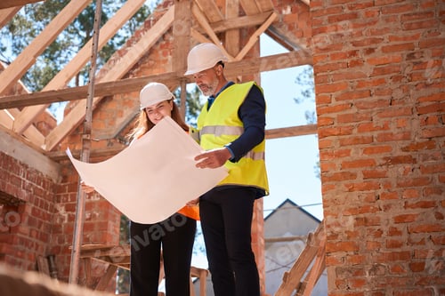 Preview: Construction workers in hardhats looking at floor plan