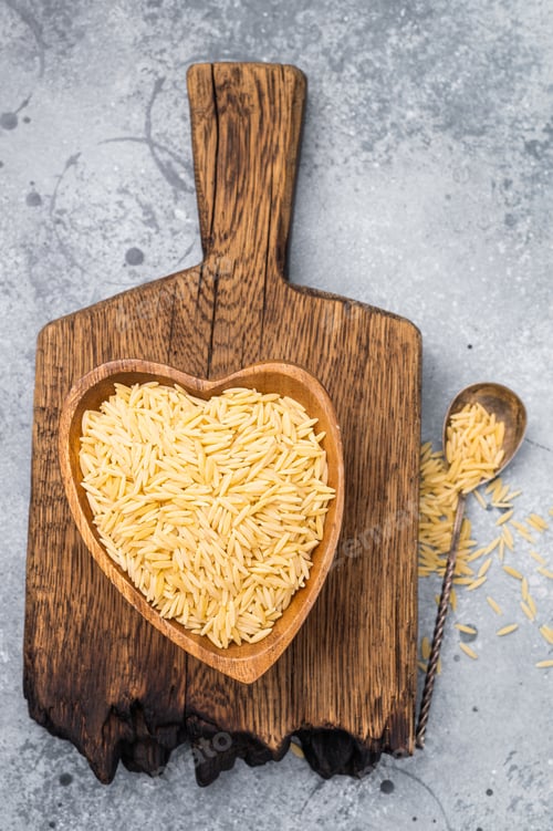 Preview: Raw Orzo pasta, uncooked dry Italian risoni in a bowl. grey background. top view