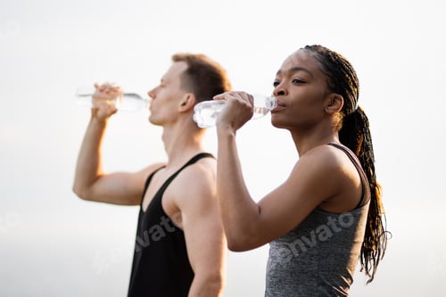 Preview: African woman and caucasian man drinking water after sport