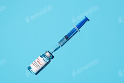Preview: Covid-19 vaccine and syringe close-up, flat lay on a blue background. Vaccination concept