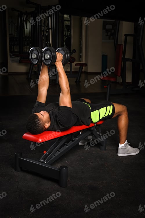 Preview: Young man doing arms bench flies workout in gym