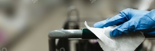 Preview: Gloved hand with a tissue paper on a shopping cart in a supermarket during the Coronavirus pandemic