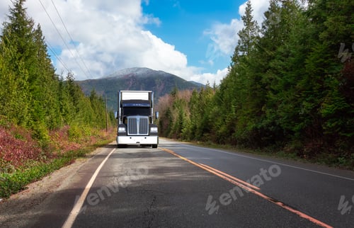 Preview: Commercial Truck Driving on Scenic Road with green Trees and Mountains in Background.