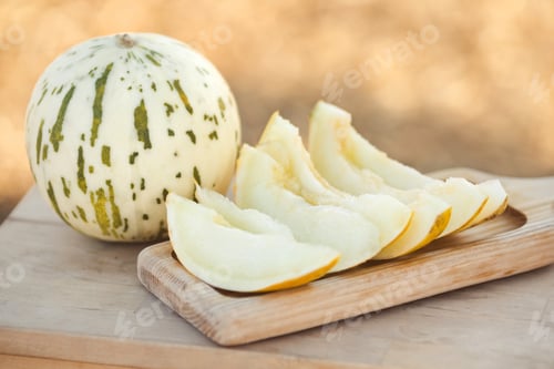Preview: Closeup honeydew melon dalmatian cut into slices and served on a wooden tray