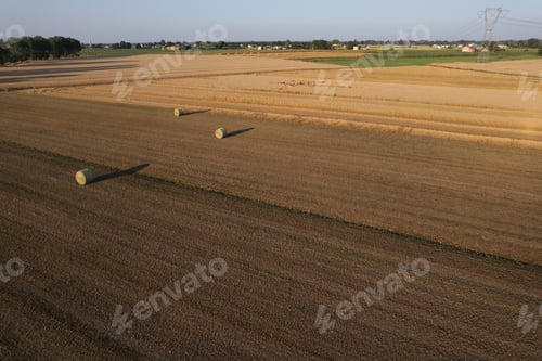 Preview: aerial view of hay ball of wheat straw in large field at early sunset in summer time