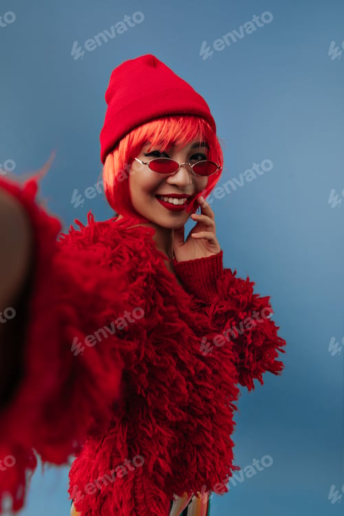 Preview: Cheerful asian girl with red short hair and pretty smile in long sleeve warm sweater, modern sungla