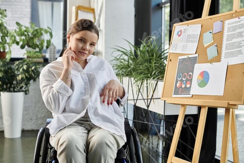 Preview: Young businesswoman in wheelchair working in modern office