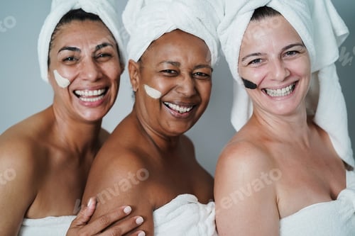 Preview: Mature women laughing together while doing beauty treatment - Main focus on right home face