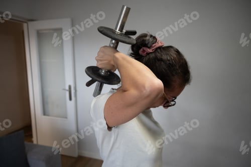 Preview: Woman doing triceps exercise with dumbbell at home