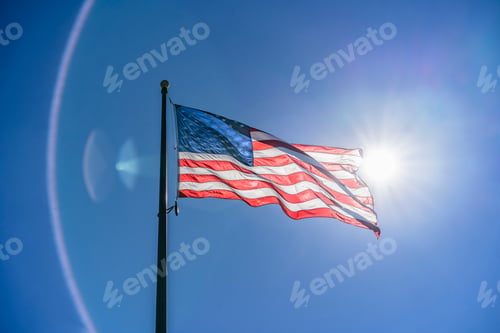 Preview: US flag waving in the wind. Vibrant colors over blue sky.