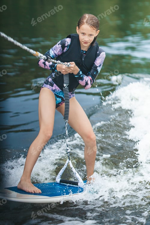 Preview: Active beautiful girl in the swimsuit standing on the wakeboard in the river