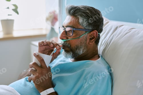 Preview: Middle Aged Biracial Man Resting in Hospital Bed and Drinking through Straw
