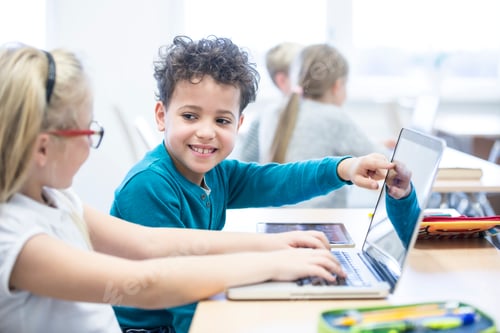 Preview: Schoolboy and schoolgirl using laptop together in class