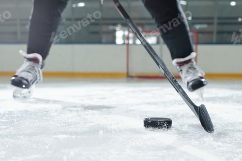 Preview: Legs of male hockey player in sports uniform and skates moving down ice rink