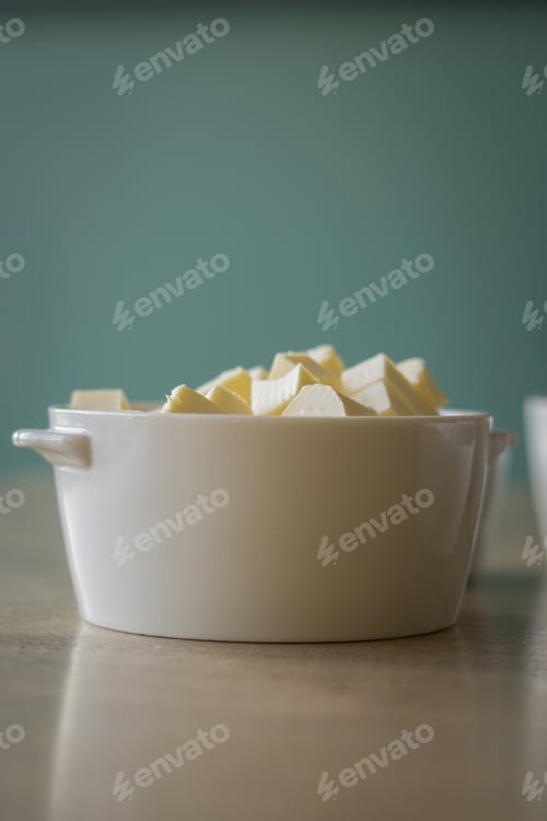 Preview: White bowl of butter cubes on a kitchen wooden table