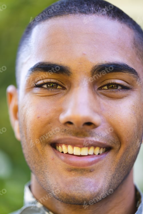 Preview: Portrait of happy biracial male soldier wearing military uniform looking at camera and smiling