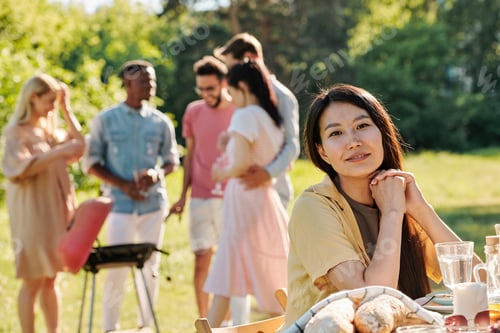 Preview: Young female of Asian ethnicity sitting by served table in front of camera