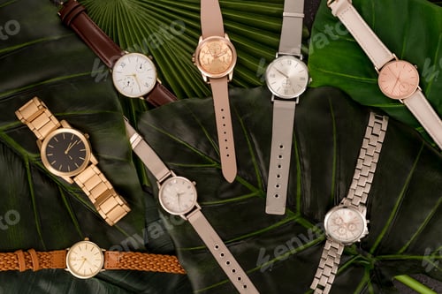 Preview: top view of elegant wristwatches lying on green leaves