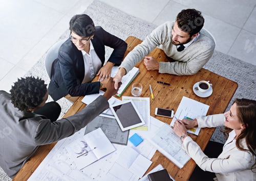 Preview: High angle shot of businesspeople shaking hands during a meeting in an office