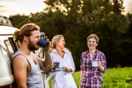 Preview: Carefree friends enjoying coffee at a van in rural landscape