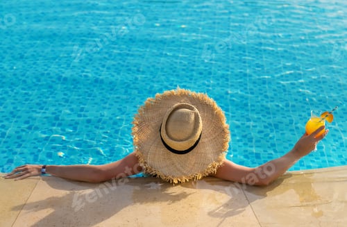 Preview: Woman with cocktail in the pool. Selective focus.