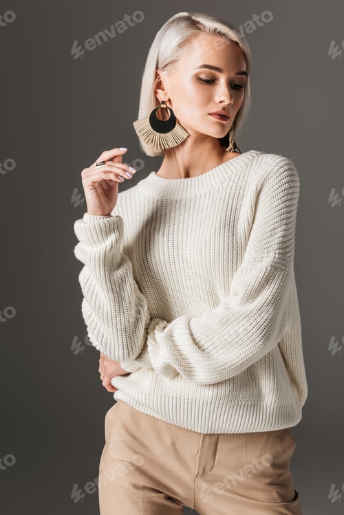 Preview: attractive elegant woman posing in white sweater and big earrings, isolated on grey