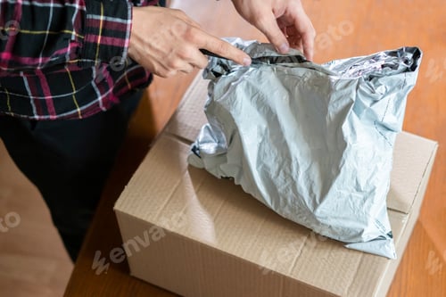 Preview: hands using knife to open the delivered package at home f