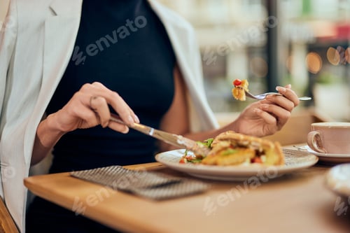 Preview: Female hands using fork and knife, eating breakfast at the restaurant.
