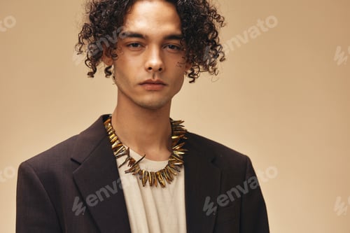 Preview: Serious stylish awesome tanned curly man in classic brown jacket ethnic necklace posing isolated on