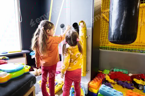 Preview: Two sisters throw balls inside tubes at kids play center.