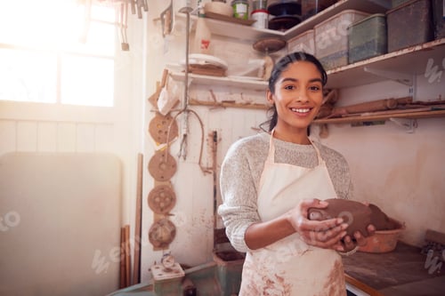 Preview: Portrait Of Female Potter Wearing Apron Holding Lump Of Clay In Ceramics Studio