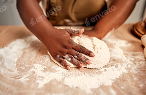 Preview: Cooking at home. Close up of plump african woman with flour on hands flattening dough on wooden tabl