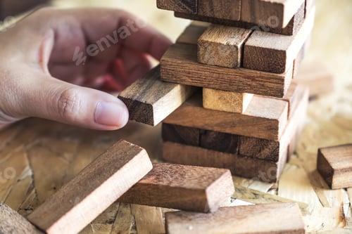 Preview: Closeup image of a hand holding and playing Tumble tower wooden block game