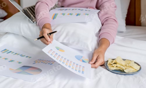 Preview: woman hand holding pen used laptop video conferences and eating snack on bed, work from home concept