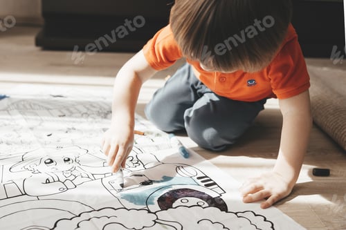 Preview: Cute little boy drawing with felt pens on floor at home. Early education concept.
