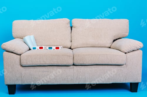 Preview: Comfortable couch with 3d glasses, popcorn isolated on blue background. Preparing for watching movie