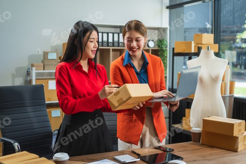 Preview: Two Asian business woman work at desk, selling fashion clothes online.They packing checking items