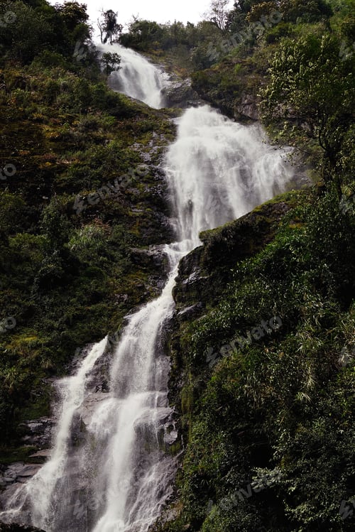 Preview: High waterfall with fresh water from the mountains streaming down through black rocks in between