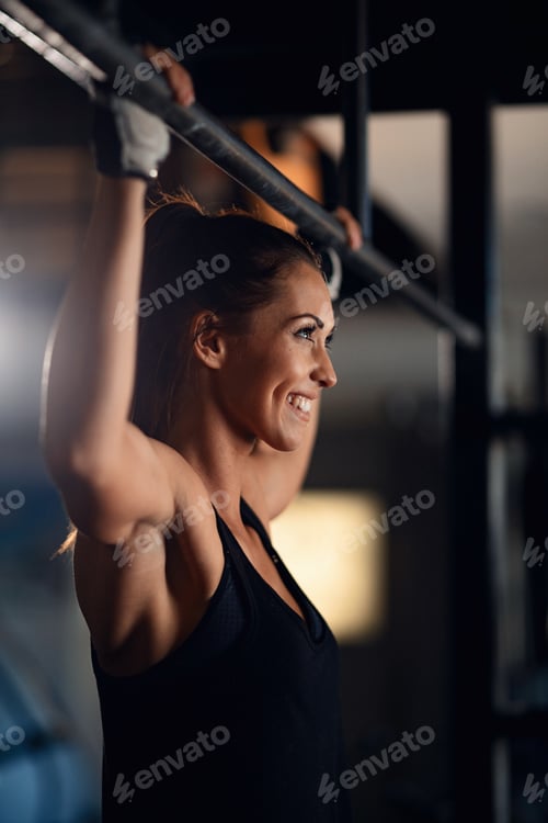 Preview: Young happy female athlete exercising in fitness center.