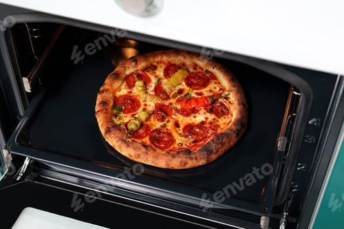 Preview: Baked pizza with sausage and pepper in the oven in the kitchen.