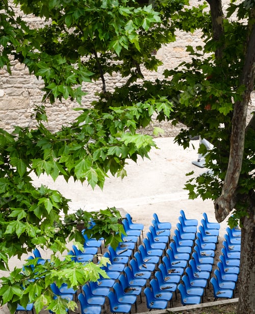 Preview: Blue seats lined up through the tree brunches on the foreground