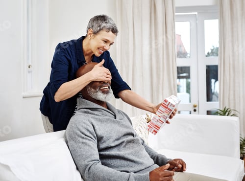 Preview: Shot of an attractive senior woman surprising her husband with a gift at home