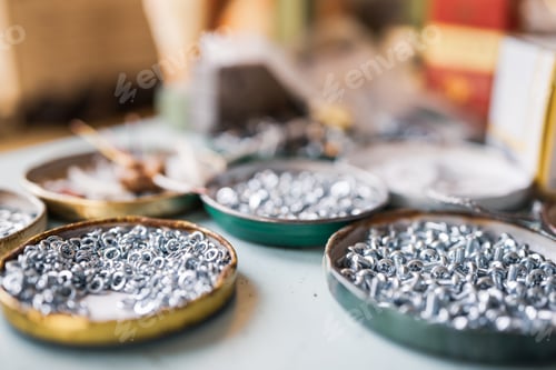 Preview: Small metal nuts bolts and a wrench lie on the work table of the assembler